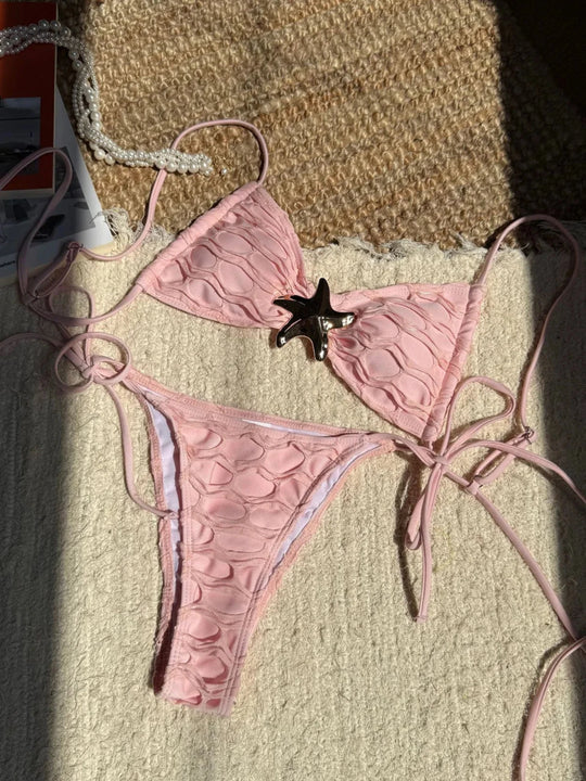 Bikini échancré à lanières et étoile métal beige rosé posé à plat sur un tapis et magazine, lanières fines