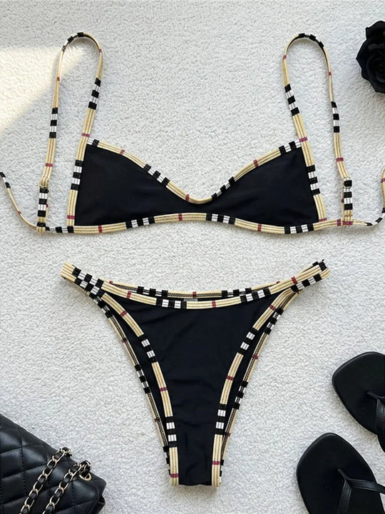 Bikini triangle sans coques taille basse à carreaux noir posé à plat sur un tissu blanc, bordure beige à carreaux