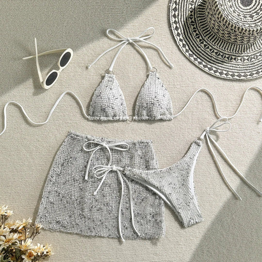 Maillot de bain trois pièces tour de cou jupe ajourée blanc pailleté posé à plat avec lunettes et chapeau tressé, haut triangle