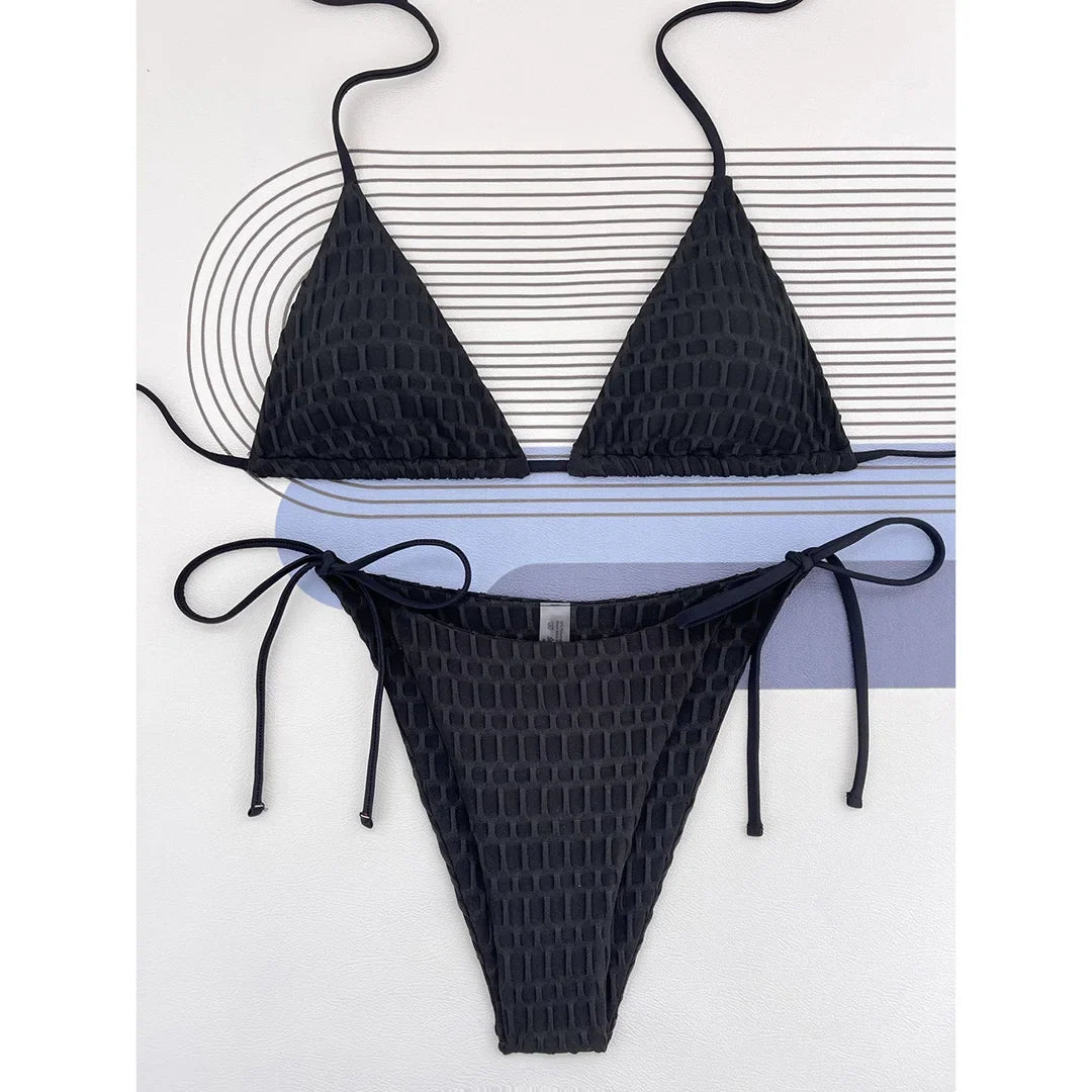 Bikini brésilien tour de cou noir texturé à plat sur un fond blanc rayé, bretelles fines et bas à liens noués