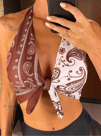 Gros plan sur le haut tour de cou noué imprimé paisley marron et blanc porté de face, nœud au centre du décolleté
