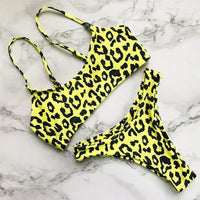 Bikini triangle brésilien à bretelles réglables jaune posé à plat sur marbre blanc, haut à bretelles fines et bas assorti à motifs noirs