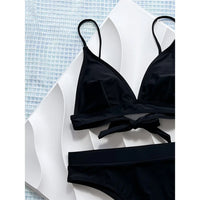 Gros plan sur le haut du bikini brésilien noir sans armatures, nœud central et bretelles fines sur fond blanc