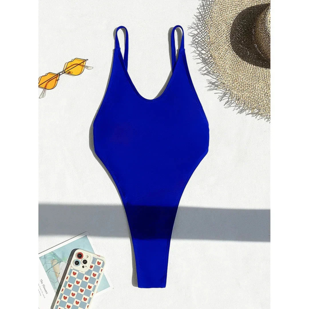 Maillot de bain une pièce bleu posé à plat sur fond blanc, bretelles fines, lunettes et chapeau à côté