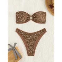 Bikini bandeau rembourré marron pailleté posé à plat sur une serviette blanche, anneau métallique au centre du bandeau