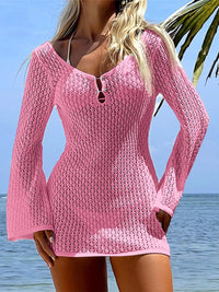 Tunique de plage en crochet à col V et manches longues rose, portée de face sur une plage au bord de la mer