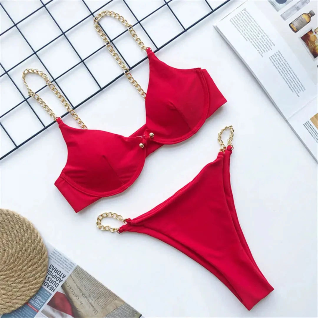 Bikini échancré à armatures avec chaîne dorée rouge posé à plat sur fond blanc, armatures et chaînes dorées sur les bretelles