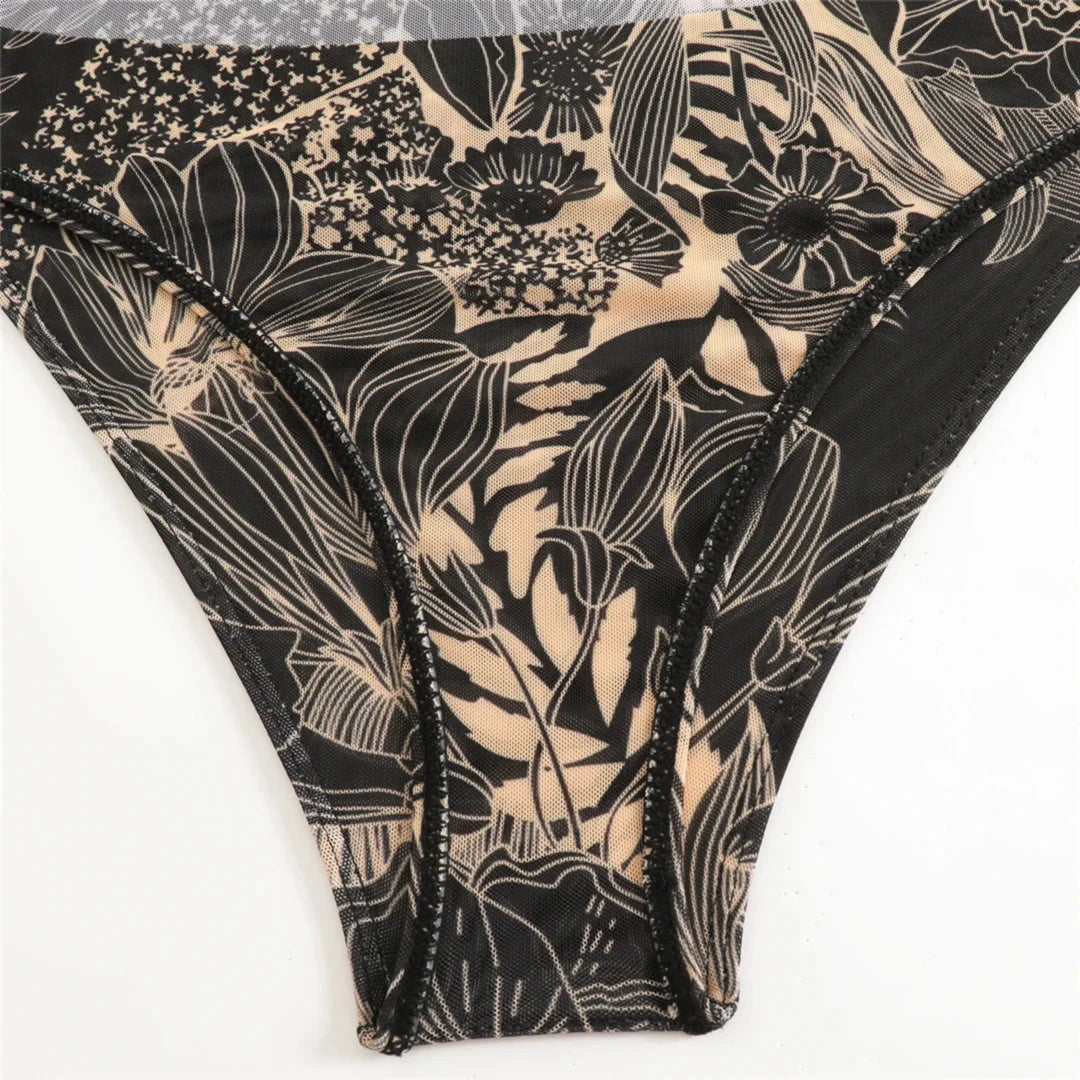 Gros plan sur la culotte du body en mesh noir à motifs floraux beiges, taille haute et bordure fine