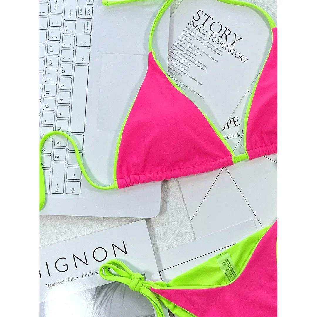 Gros plan sur le haut triangle rose fuchsia bordé de vert fluo, bretelles fines posées sur un clavier
