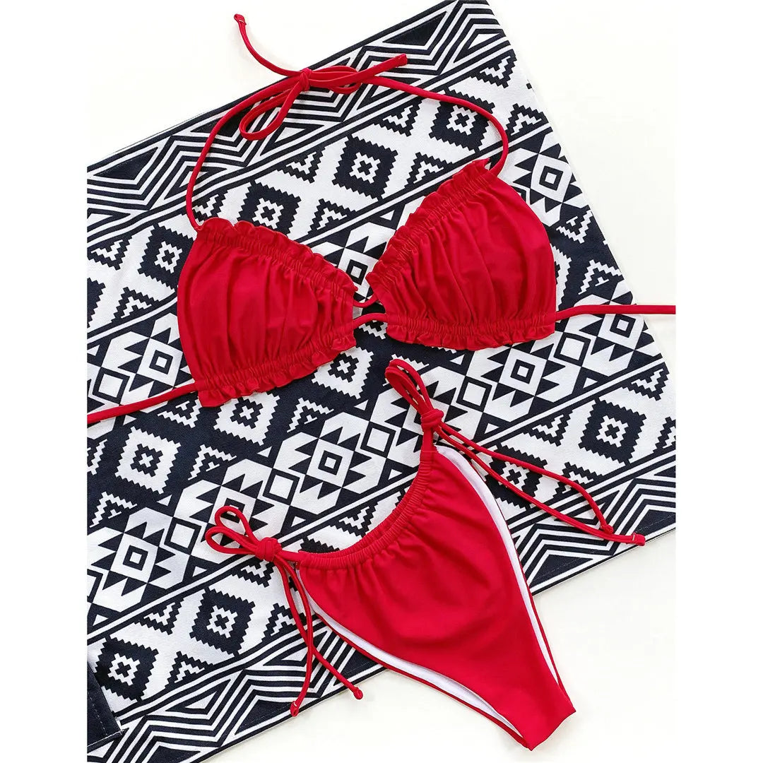 Bikini à volants froncé col halter bas à nouer rouge à plat sur un tapis géométrique noir et blanc