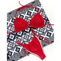 Bikini à volants froncé col halter bas à nouer rouge à plat sur un tapis géométrique noir et blanc