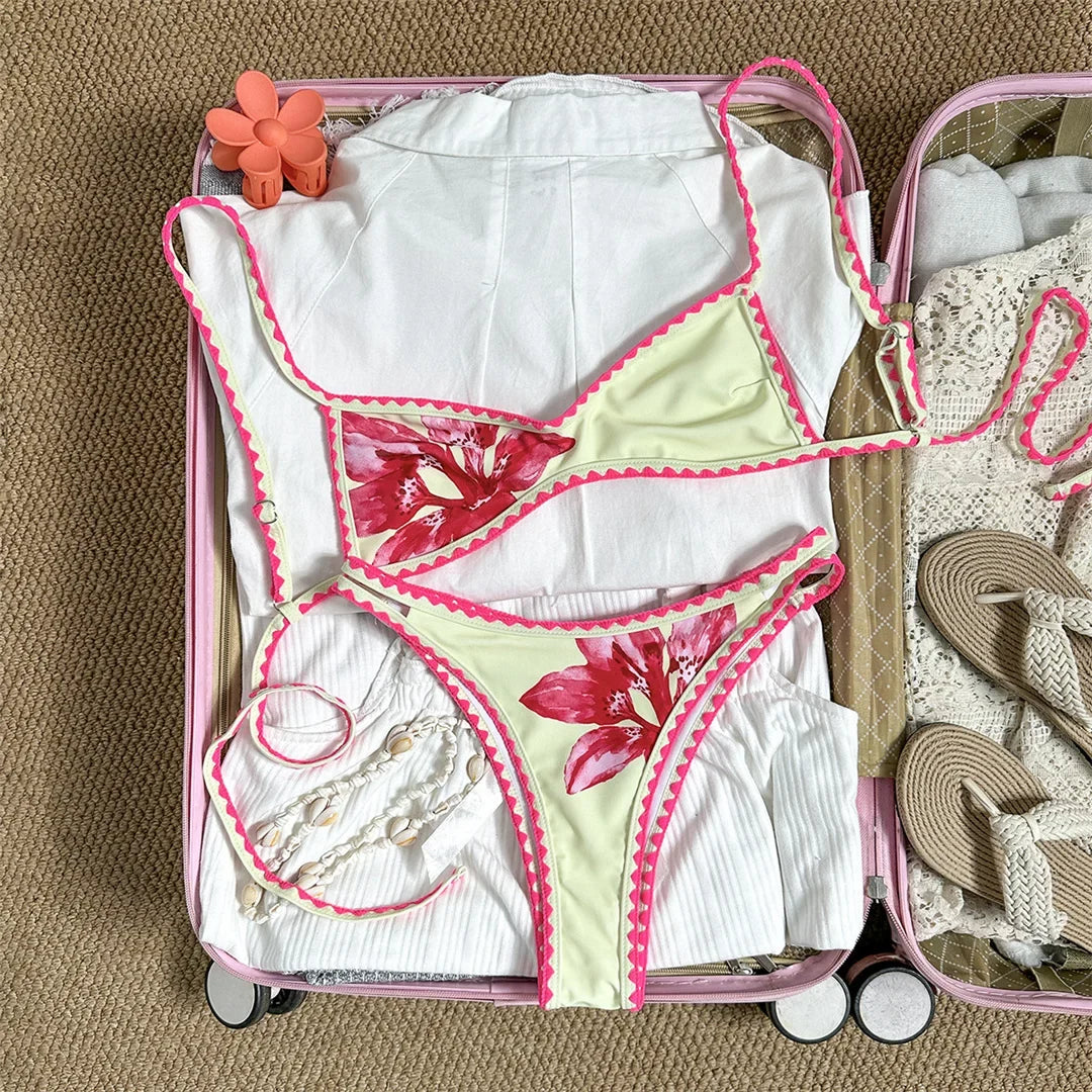 Bikini brésilien triangle imprimé fleuri beige à plat dans une valise, fleurs roses et liseré rose au crochet