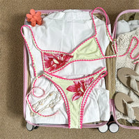 Bikini brésilien triangle imprimé fleuri beige à plat dans une valise, fleurs roses et liseré rose au crochet