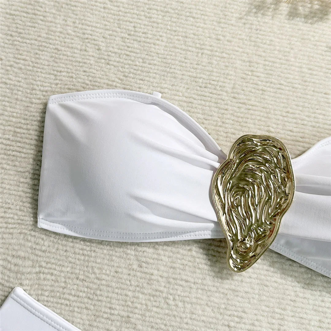 Gros plan sur le haut bandeau blanc et l'anneau métallique doré en forme de goutte à texture ciselée
