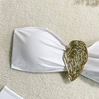 Gros plan sur le haut bandeau blanc et l'anneau métallique doré en forme de goutte à texture ciselée