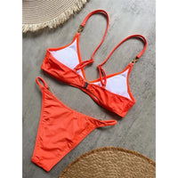 Bikini triangle orange vu de dos posé à plat sur un sol gris, doublure blanche et bretelles croisées aux anneaux strassés