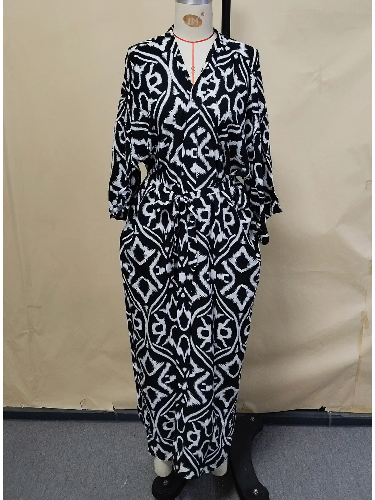 Robe de plage imprimée à manches longues col V noir de face en pied, manches évasées et ceinture nouée à la taille