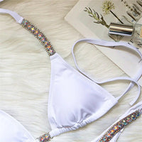 Gros plan sur le haut triangle blanc à bretelles ornées de strass multicolores, sur fond blanc