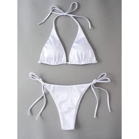 Bikini brésilien satiné triangle tour de cou blanc posé à plat sur fond gris, liens latéraux longs