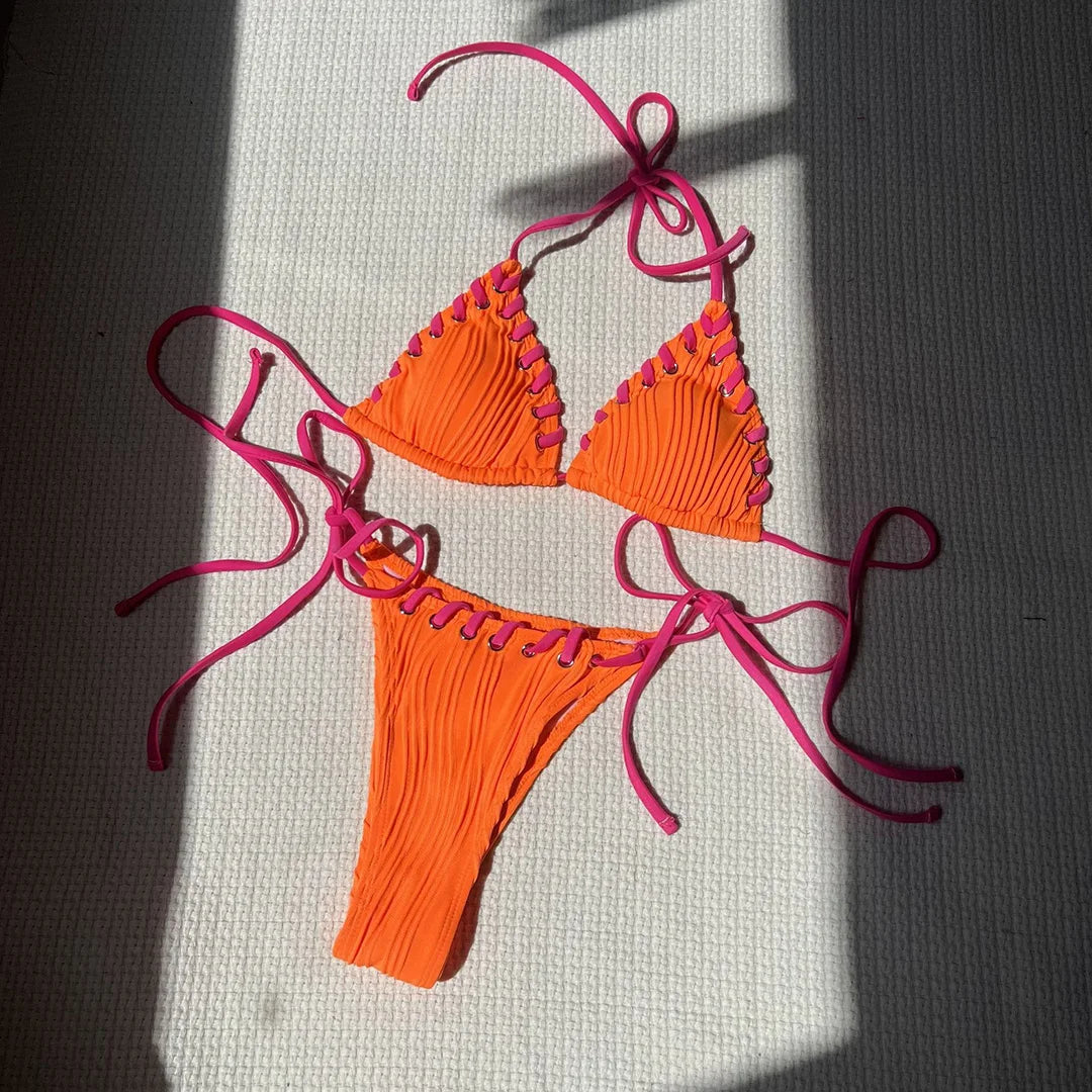 Bikini tour de cou rouge orangé posé à plat sur un tapis blanc, bordures festonnées et liens longs au soleil
