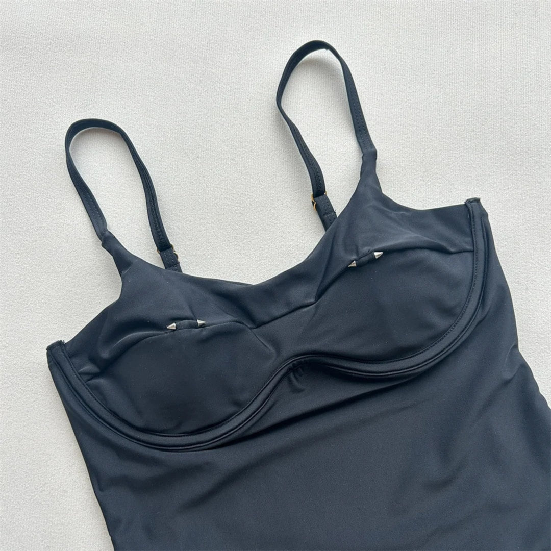 Gros plan sur le haut noir du maillot de bain échancré, boucle dorée au centre de la découpe et bretelles fines