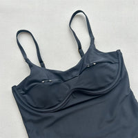 Gros plan sur le haut noir du maillot de bain échancré, boucle dorée au centre de la découpe et bretelles fines