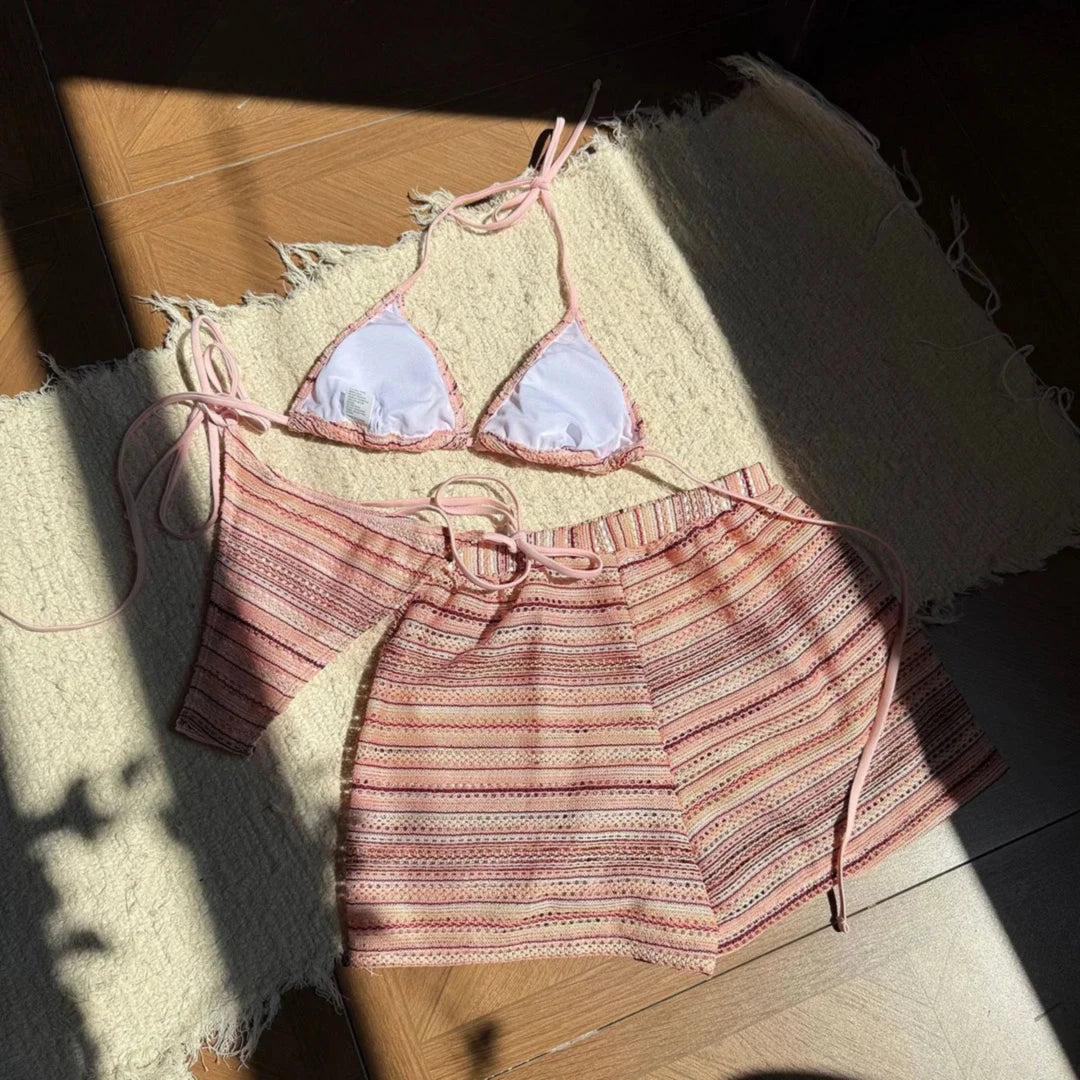 Haut triangle à doublure blanche et short rayé rose pêche posés à plat sur un tapis, lanières nouées
