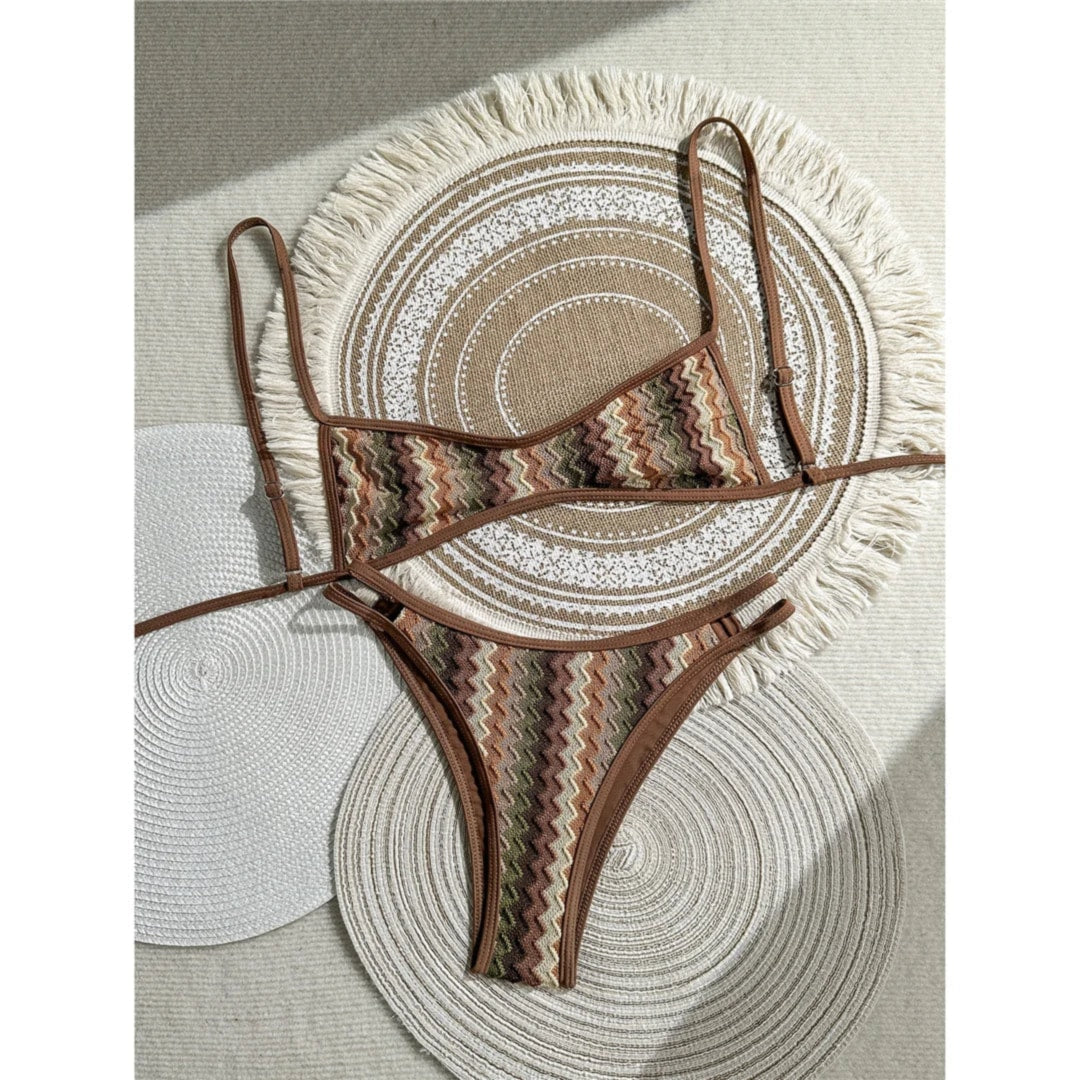 Bikini brésilien triangle sans armatures rayé marron et vert posé à plat sur des sets en paille, bordure marron et bretelles