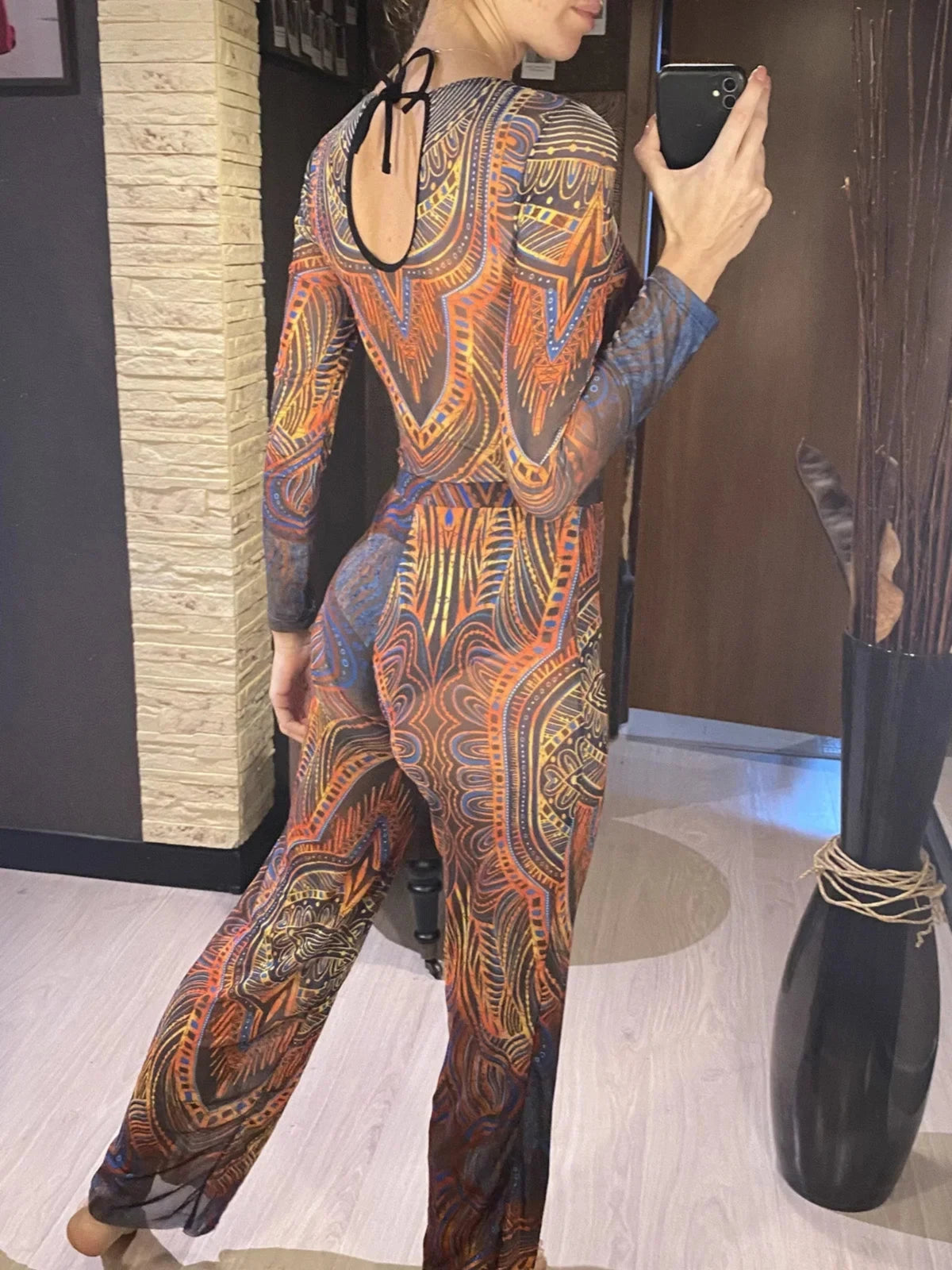 Maillot de bain une pièce manches longues et pantalon bleu à motifs orange, porté de dos avec lien noué au col