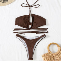 Bikini tour de cou à lacets croisés sans armatures marron café posé à plat sur un tapis, lacets longs et sac en paille