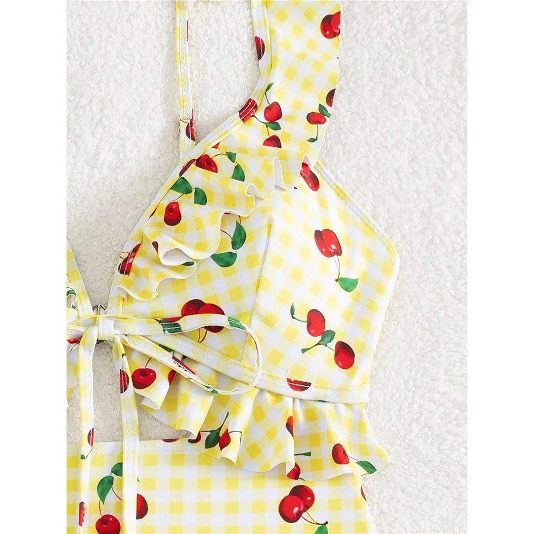 Gros plan sur le décolleté du maillot de bain jaune clair à cerises, volants et lien noué au centre