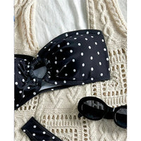 Gros plan sur le bandeau noir à pois blancs et son anneau central, posé sur un tissu crochet crème