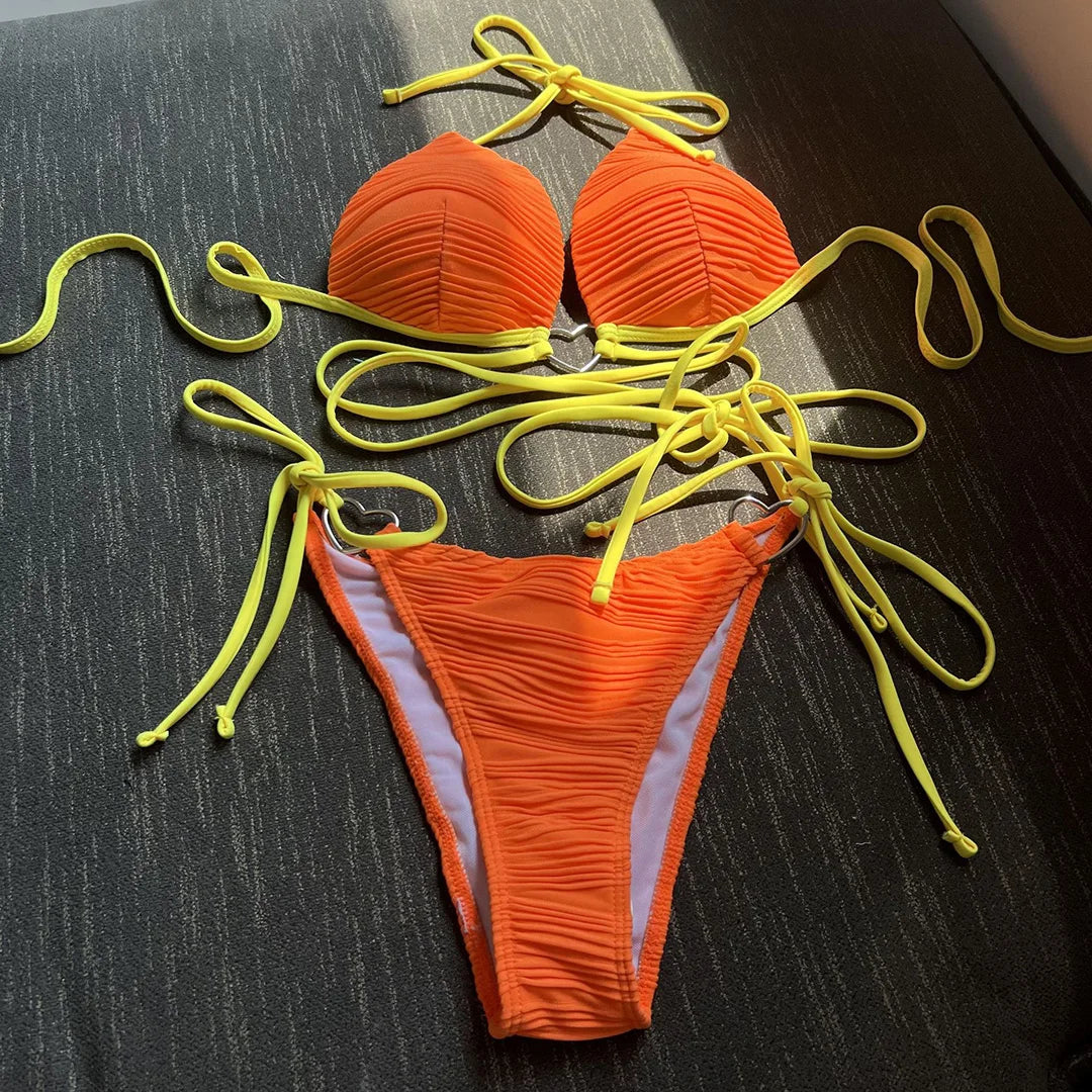 Bikini col halter croisé à effet froissé rouge orangé posé à plat, lacets jaune fluo longs et slip froncé