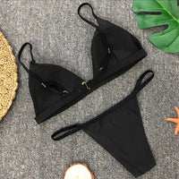 Bikini brésilien rembourré à taille basse noir posé à plat, anneau métallique central et bretelles fines
