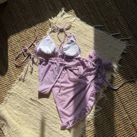 Maillot violet clair à plat vu de l'intérieur, doublure blanche visible sur le haut et pareo volanté posé dessus