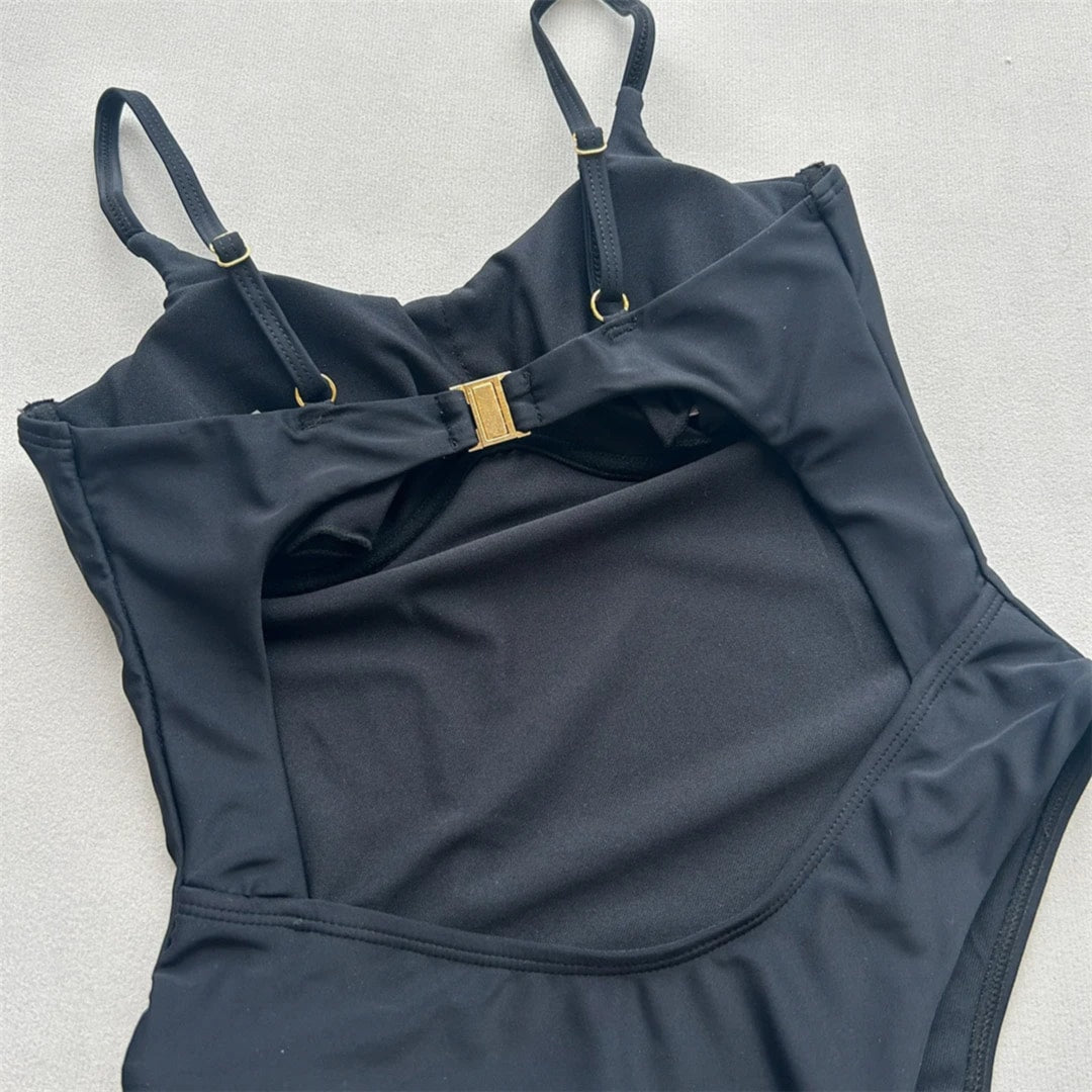 Gros plan sur la découpe noire du maillot de bain échancré, boucle dorée centrale et bords de la coupe haute