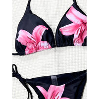Gros plan sur le haut triangle noir à grandes fleurs roses d'un bikini, bonnets froncés et bordure élastique