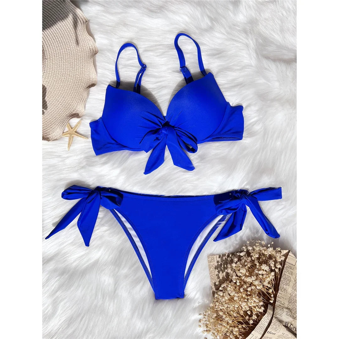 Bikini push-up noué avec armatures et rembourrage bleu roi posé à plat sur fourrure blanche, nœud central sur le haut