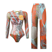 Maillot de bain une pièce manches longues et pantalon imprimé zèbre posé à plat, feuillage orange et bleu sur fond blanc