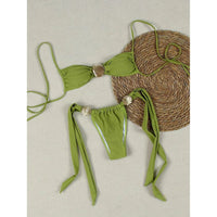 Bikini tour de cou à détail coquille métallique échancré vert à plat sur fond beige, coquille dorée au centre