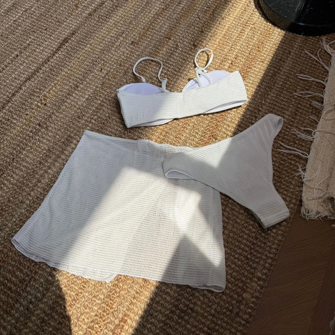 Bandeau blanc à bretelles fines posé à plat, vue en plongée, bas brésilien et jupe fendue au premier plan