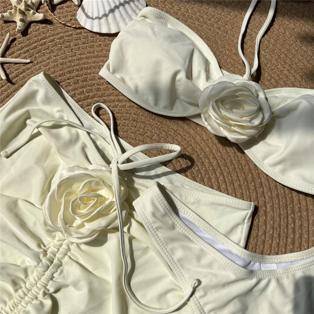 Gros plan sur la fleur en relief blanc cassé du bustier, jupe froncée et bas posés à plat sur tissu clair