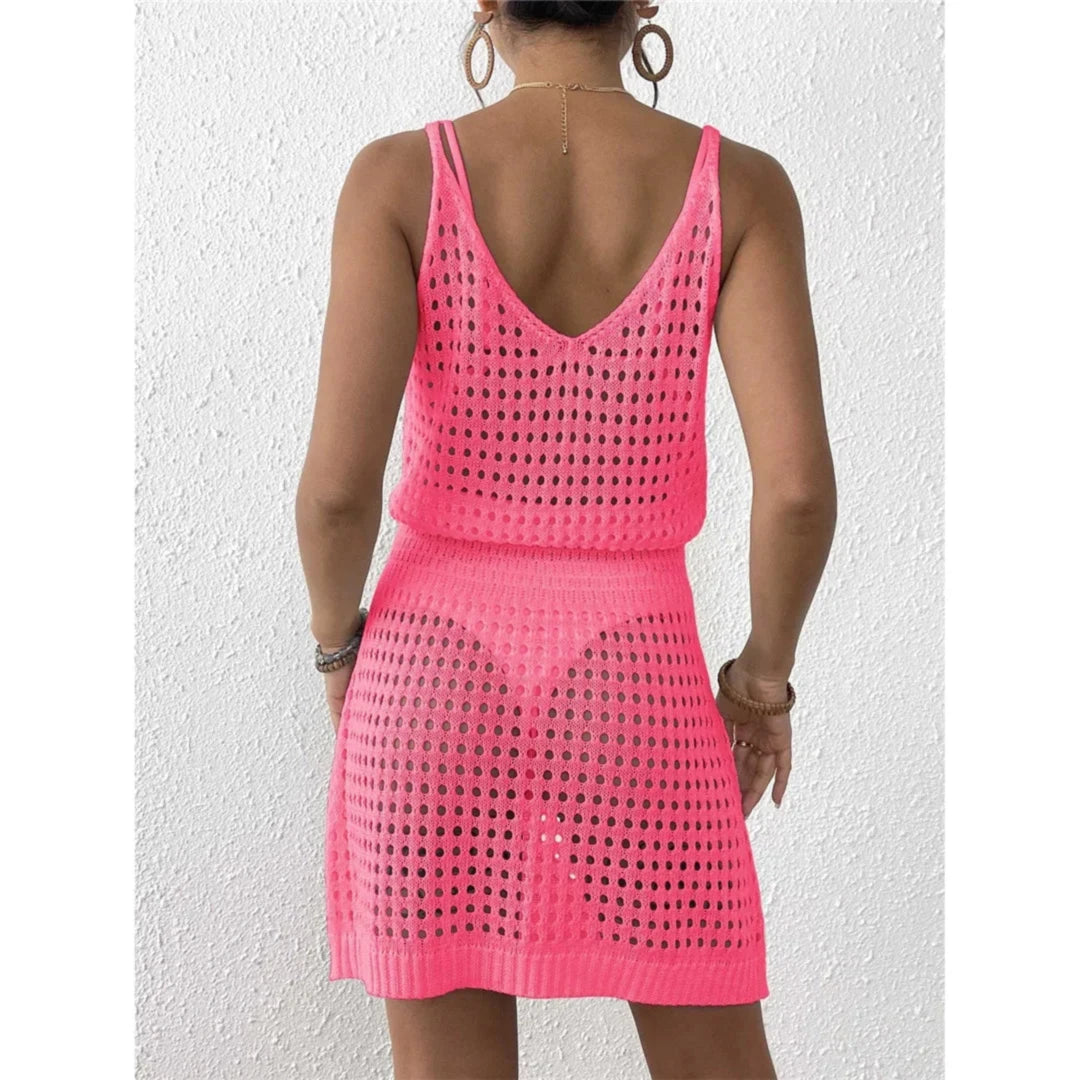 Tunique de plage en crochet ajourée rose fuchsia vue de dos, dos en V, sur un mur blanc