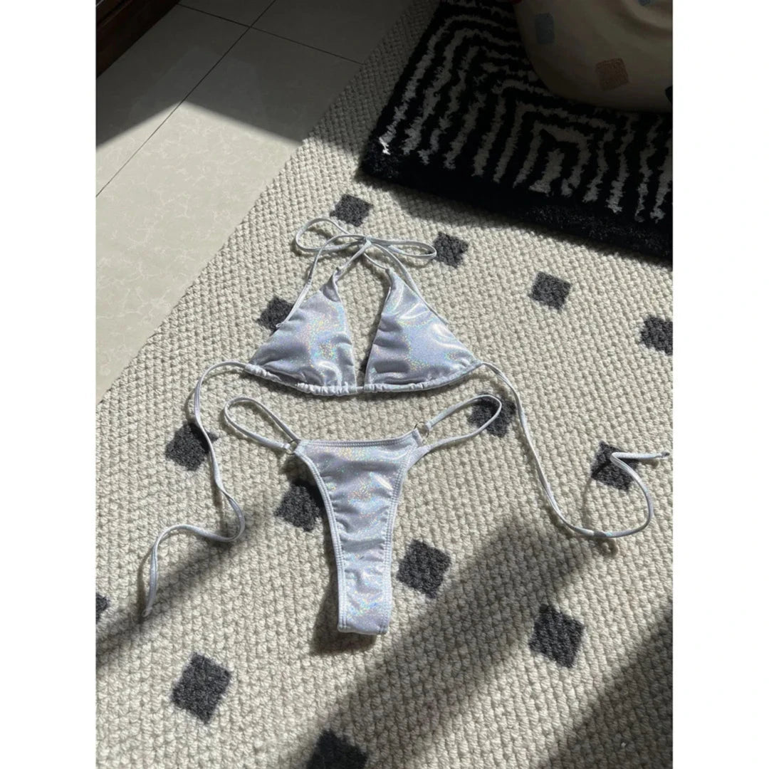 Bikini brillant scintillant triangle taille basse blanc posé à plat sur un tapis, liens longs et culotte fine