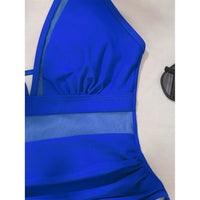 Gros plan sur le buste du maillot bleu foncé, décolleté en V bordé de mesh transparent et taille froncée
