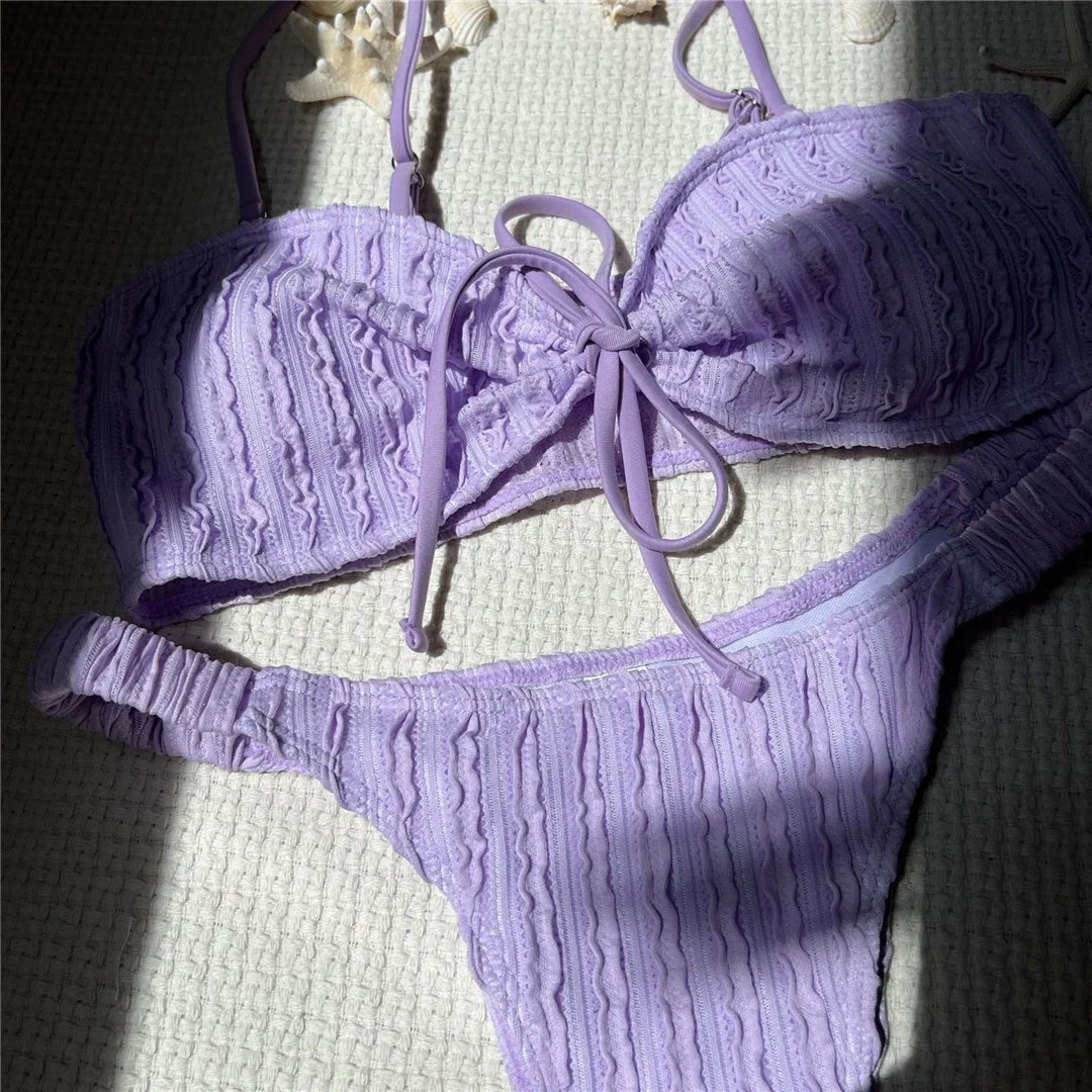 Gros plan sur le haut violet texturé avec son nœud central, bretelles fines et texture en vagues