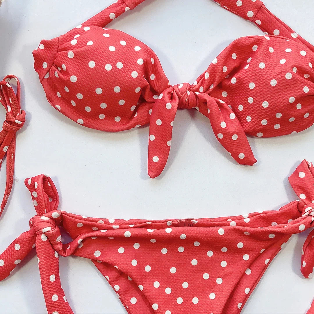 Gros plan sur le haut bandeau orange à pois et le bas à lacets, posés à plat sur un fond blanc