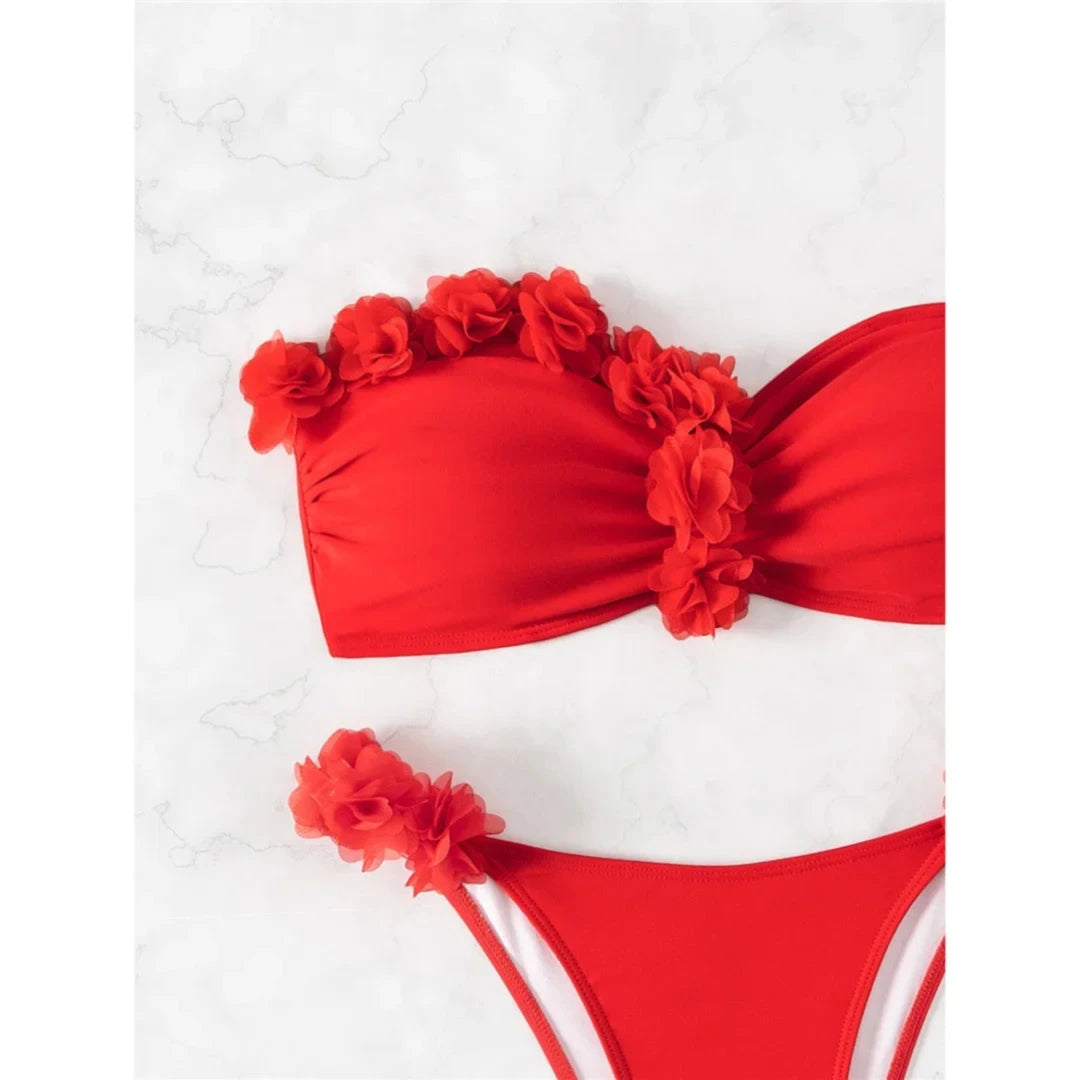 Gros plan sur le bandeau rouge orné de fleurs en tissu en relief et la fleur fixée sur le côté du bas de maillot
