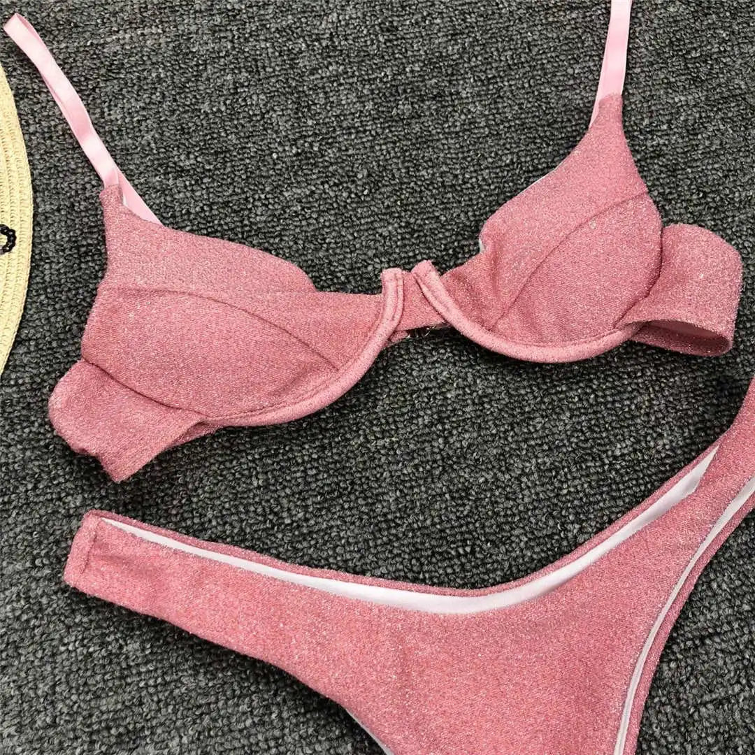 Gros plan sur le haut rose à armatures et bordure fine, posé sur un tapis gris