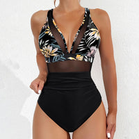 Maillot de bain une pièce en mesh imprimé feuilles porté de face par une femme, haut à fleurs et feuilles sur fond noir et bas noir uni